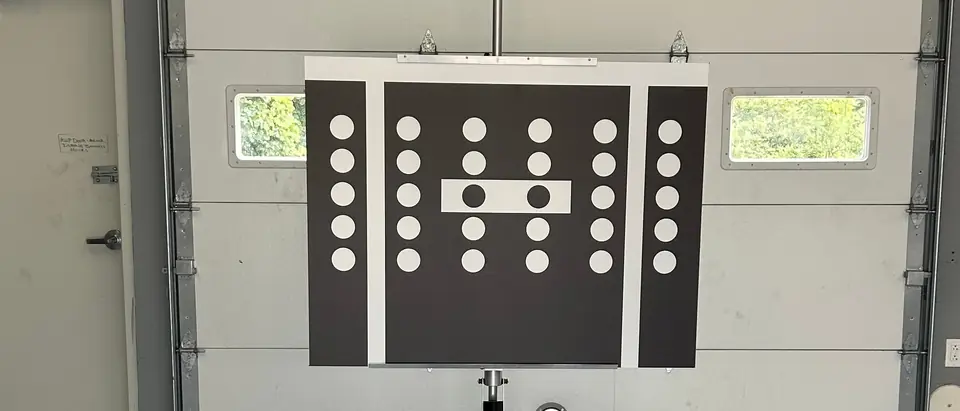A camera calibration target board set up on a stand in front of a garage bay door