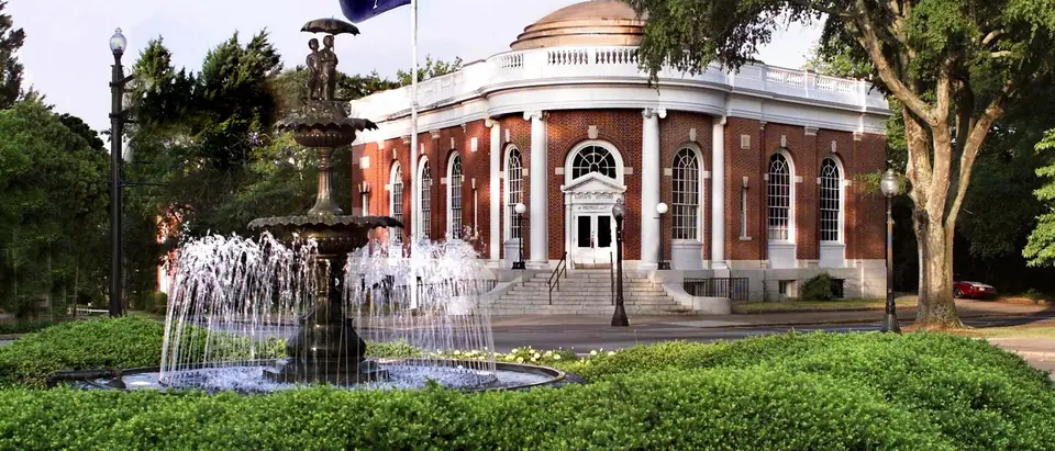 The old post office in downtown Aiken, SC, a red-brick domed building behind a fountain and green lawn
