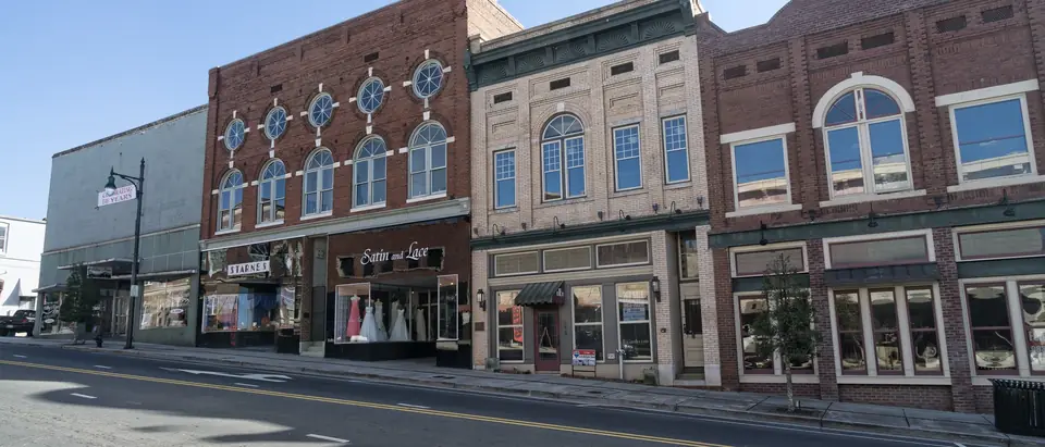 A row of historic brick storefronts on a sunny street in downtown Albemarle, NC