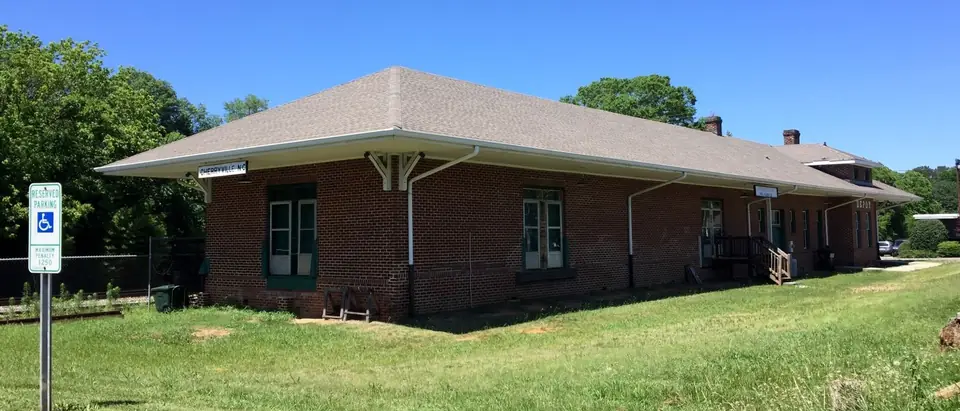 The old red-brick railroad depot on a green lawn under a blue sky in Cherryville, NC