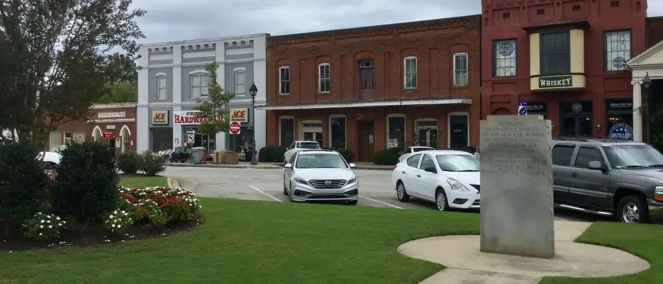 The historic brick storefronts around the town square in Edgefield, SC, with flower beds in front