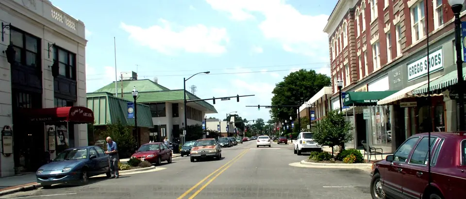 Main Street in downtown Elizabeth City, NC, lined with historic brick buildings under a blue sky