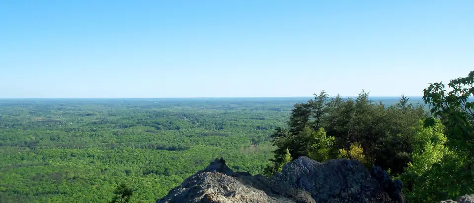 The view from the rocky summit of Crowders Mountain over the forests of Gaston County, NC, under a clear blue sky