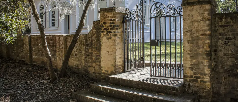 The white colonial St. James Goose Creek church behind its brick wall and iron gate in Goose Creek, SC