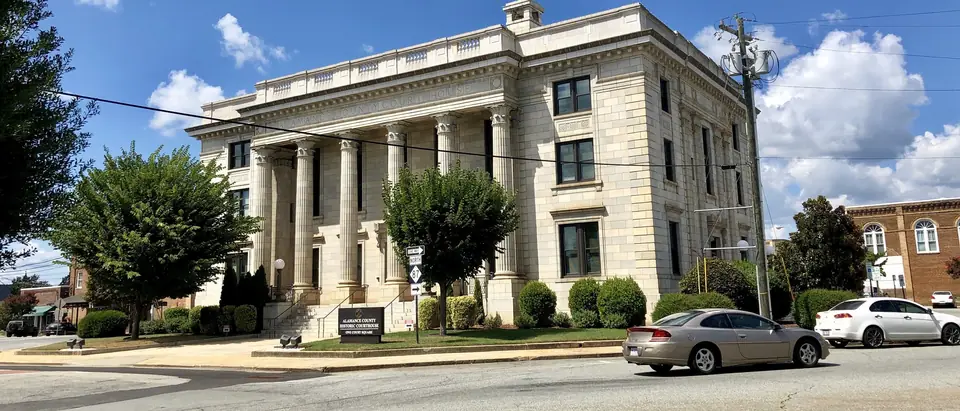 The white marble Alamance County Courthouse under a blue sky with white clouds in downtown Graham, NC