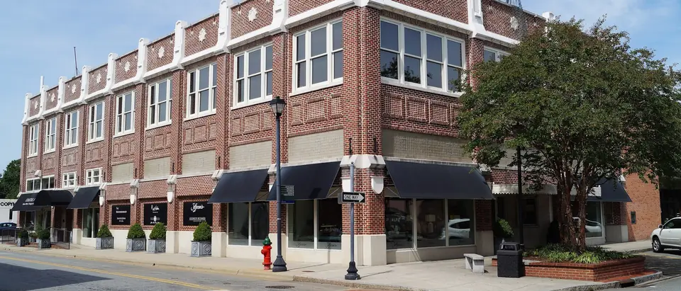 A restored red-brick commercial building on a sunny corner in downtown Greenville, NC