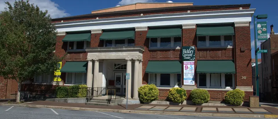 The brick Hickory Municipal Building with green awnings under a blue sky in downtown Hickory, NC