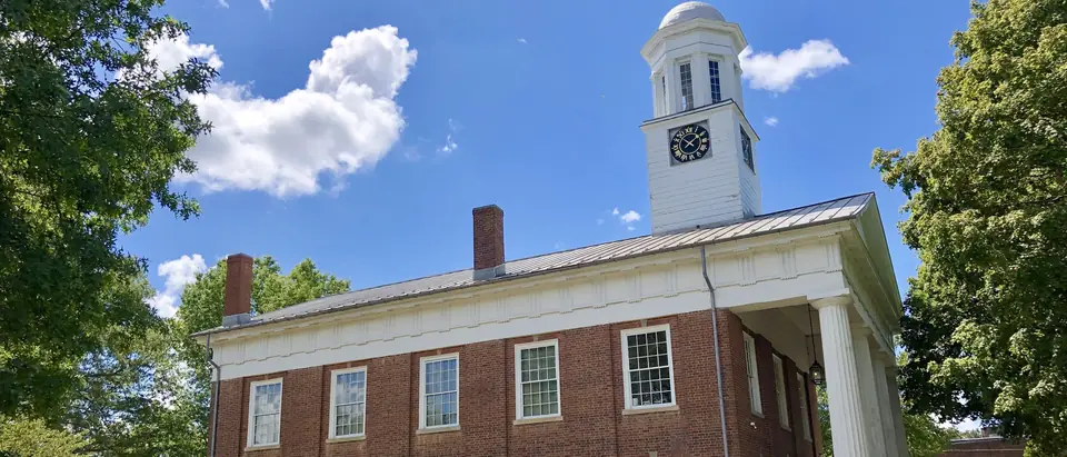 The red-brick Old Orange County Courthouse with its white clock cupola under a blue sky in Hillsborough, NC