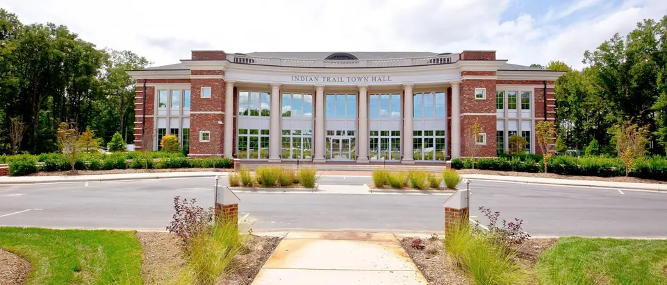The brick and white-columned Indian Trail Town Hall behind landscaped lawns in Indian Trail, NC