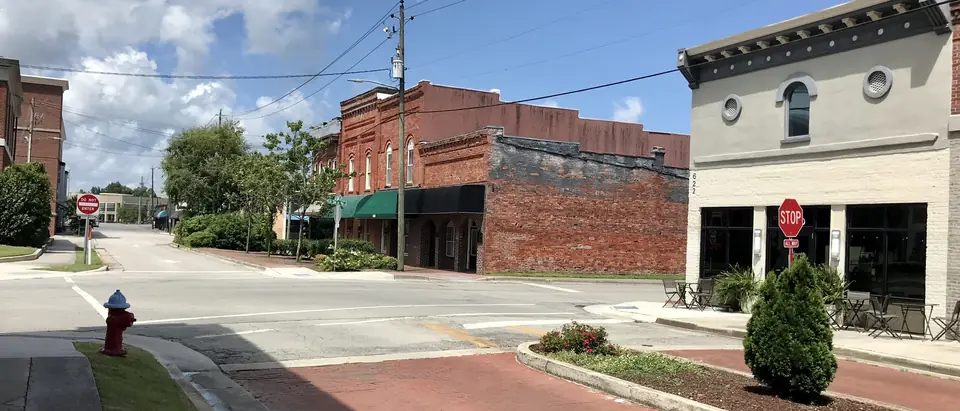 Historic brick and stucco buildings along Court Street in downtown Jacksonville, NC, under a blue sky