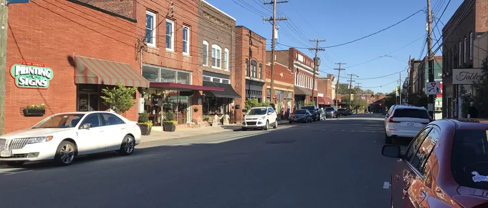 Clay Street in downtown Mebane, NC, with brick shops and awnings under a deep blue sky