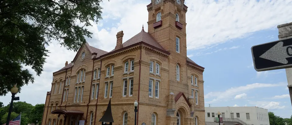 The yellow-brick Newberry Opera House with its clock tower on a street corner in downtown Newberry, SC