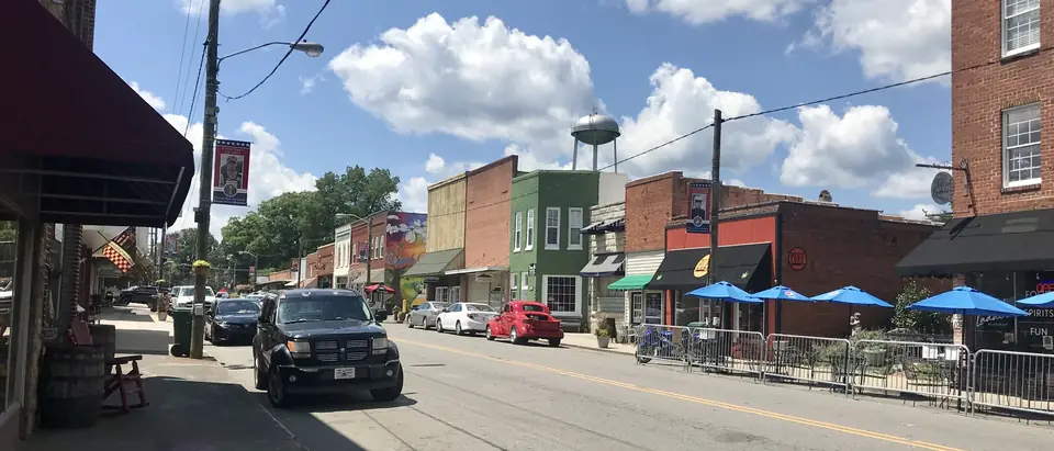 Main Street in downtown Pilot Mountain, NC, with brick shops and blue umbrellas under a summer sky