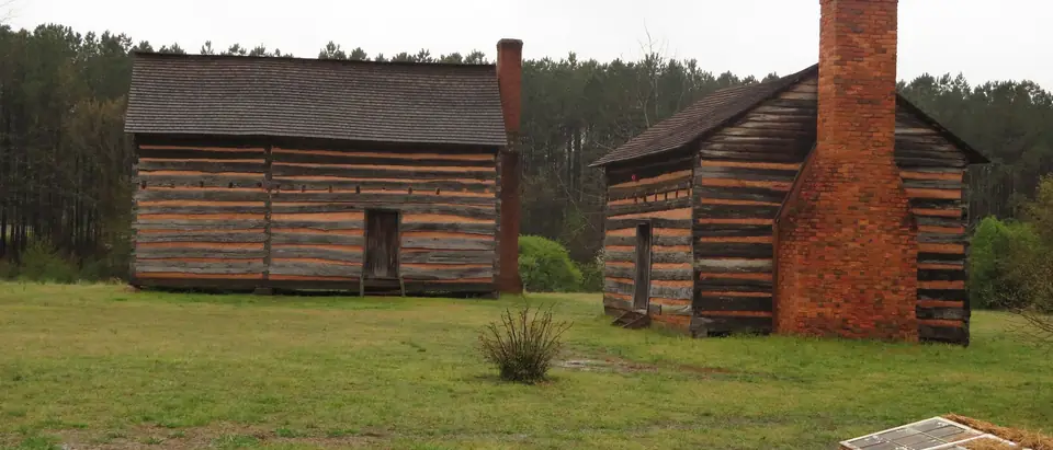 Log cabins with a brick chimney at the President James K. Polk birthplace historic site in Pineville, NC