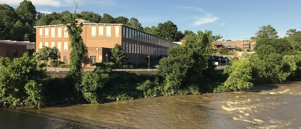 The old brick spinning mill above the Haw River in the village of Saxapahaw, NC, on a sunny day