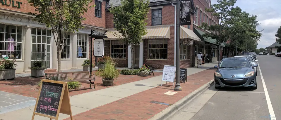 Shops with brick sidewalks and lamp posts along Broad Street in downtown Southern Pines, NC