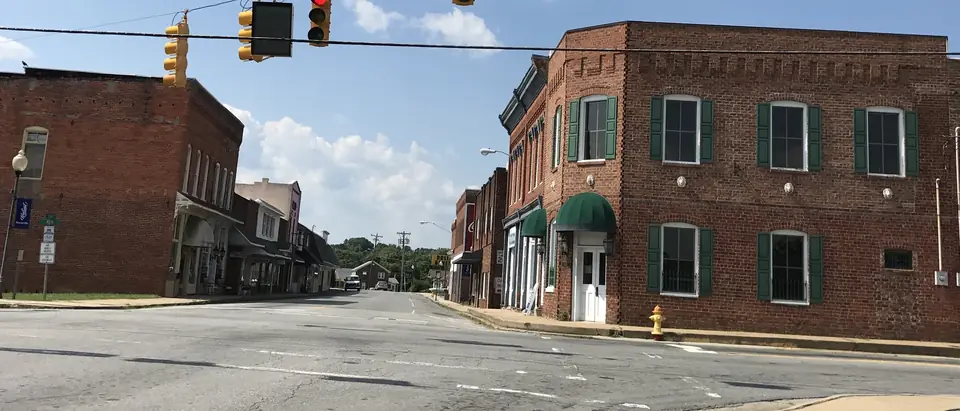 Historic red-brick buildings at the main crossroads of downtown Stoneville, NC, under a blue sky