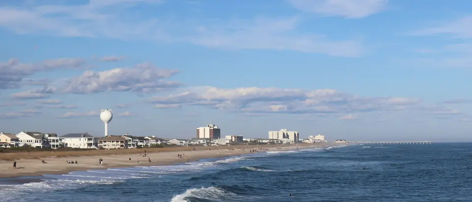 The beach and ocean waves at Wrightsville Beach, NC, with hotels and a water tower along the shore